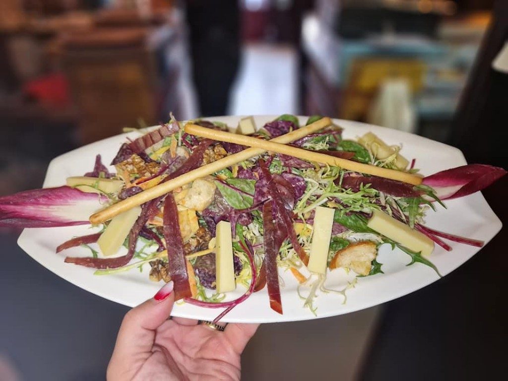 Une salade composée aux endives, noix et vinaigrette, tenue à la main
